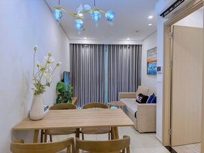 A modern living room with a dining table, sofa, and decorative plants. - The Song Luxury Apartment-Livi Homestay (Ho Chi Minh City)