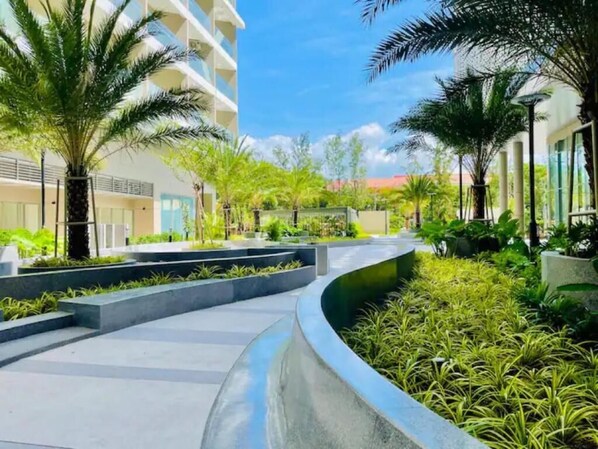 A modern hotel courtyard with a curved pathway, palm trees, and lush greenery. - The Song Luxury Apartment-Livi Homestay (Ho Chi Minh City)