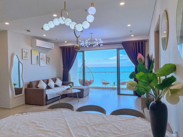 Une chambre moderne avec un balcon, un canapé, un fauteuil suspendu et un grand miroir.