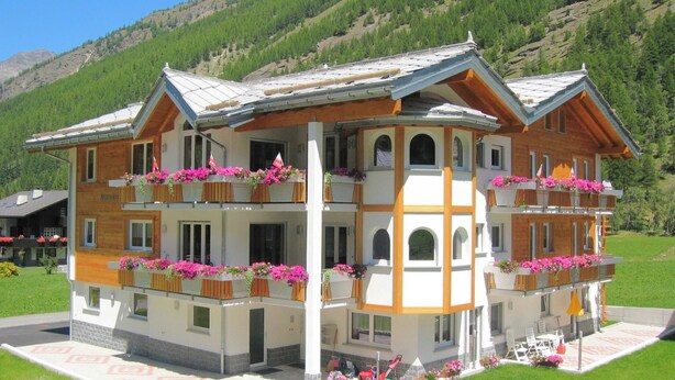 Un hôtel à plusieurs étages doté de balcons, d’une cour intérieure et surplombant un paysage montagneux.