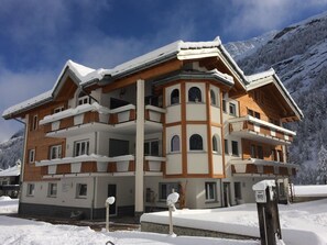 A multi-story building with a snow-covered roof and balconies, surrounded by a mountainous landscape. - Alpenstern by Interhome (Saas-Grund)