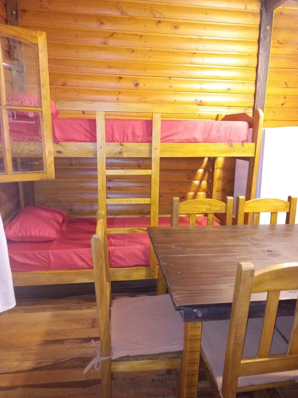 Una cabaña con literas, una mesa de madera y sillas.