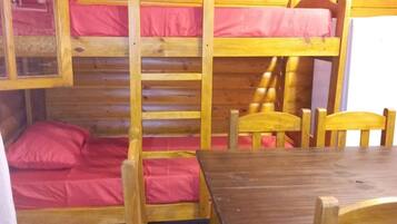 Una cabaña con literas, una mesa de madera y sillas.