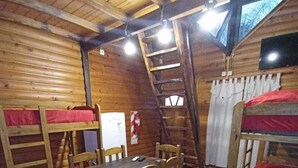 A cozy cabin interior with wooden walls, a dining table, chairs, bunk beds, a ladder, and a small kitchenette. - Cabañas Misioneras  (San Ignacio)