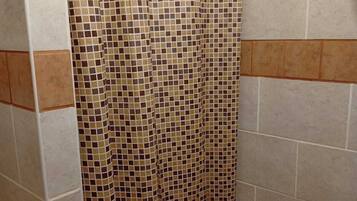 A bathroom with a tiled shower curtain, a toilet, and a urinal.