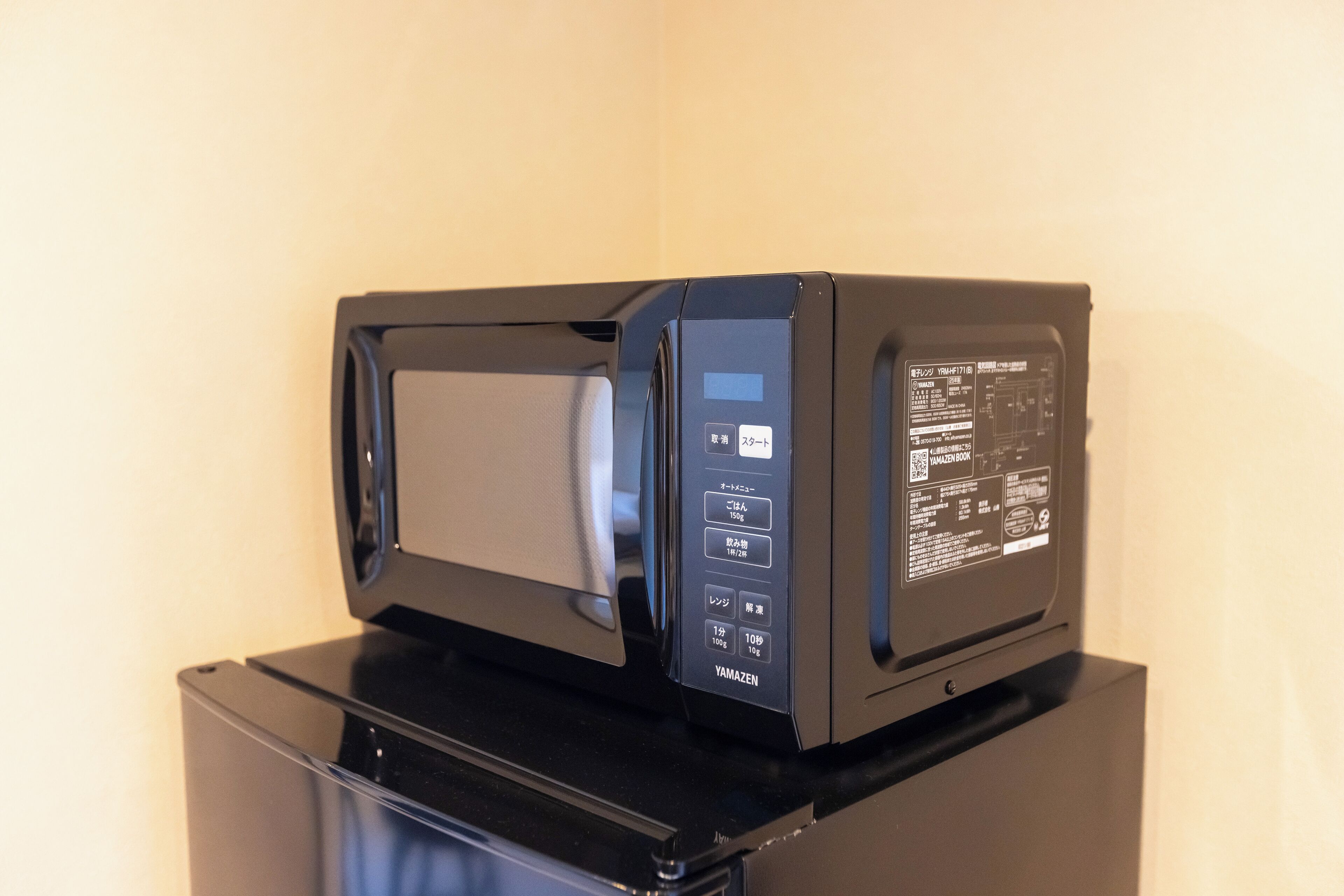Un horno microondas negro con pantalla digital y panel de control, sobre una superficie negra.