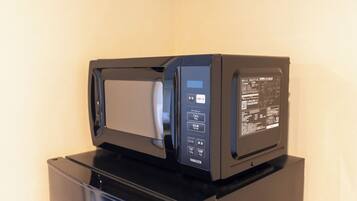 Un horno microondas negro con pantalla digital y panel de control, sobre una superficie negra.
