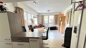 Un espacio habitable compacto con kitchenette, comedor y una pequeña zona de estar.