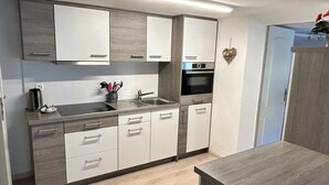 Una cocina moderna con armarios blancos, un lavamanos de acero inoxidable y un horno empotrado.