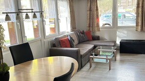 Una sala de estar moderna con un sofá, una mesa de comedor y una mesa de centro de vidrio.