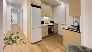 A modern kitchen with a refrigerator, microwave, stove, and sink. - Apartment + Office in Delicias (Madrid)