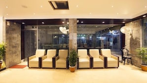 Un hall d’entrée avec un espace salon, une grande colonne et un mur en verre.