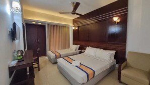 Une chambre d’hôtel avec deux lits, un bureau, une chaise, un ventilateur de plafond et une fenêtre avec des rideaux.