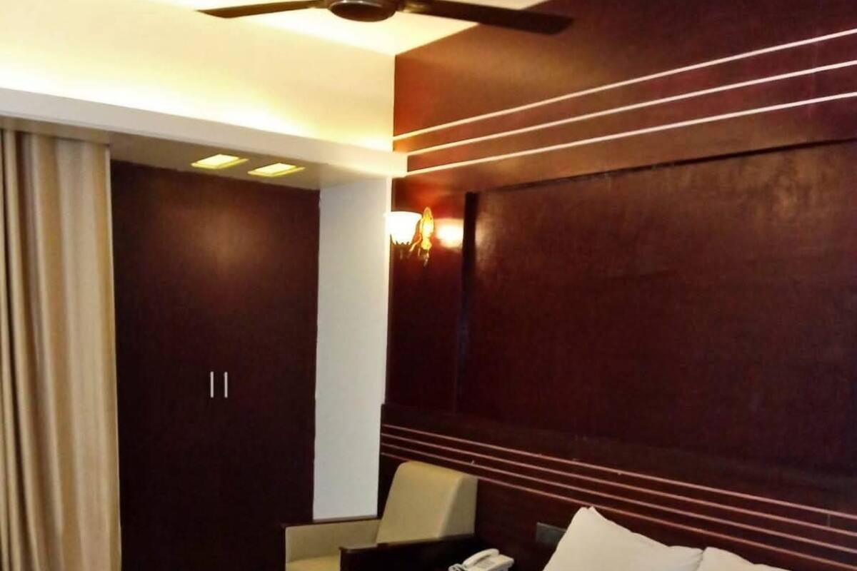 Una habitación de hotel con una cama grande, un escritorio, una silla, un teléfono y un ventilador de techo.