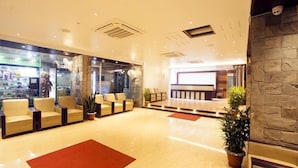 Un hall d’hôtel comprenant un comptoir d’accueil, un espace salon et une façade vitrée.