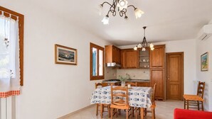 Eine Küche mit Holzausstattung, einem Esstisch mit Stühlen, einer Kandelaber und einem roten Sofa.