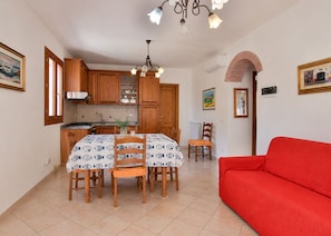 A compact living space with a dining area, kitchen, and a red sofa. - Three-room apartment Angela, in a quiet area 5 minutes from Marina di Campo, with furnished outdoor (Campo nell'Elba)