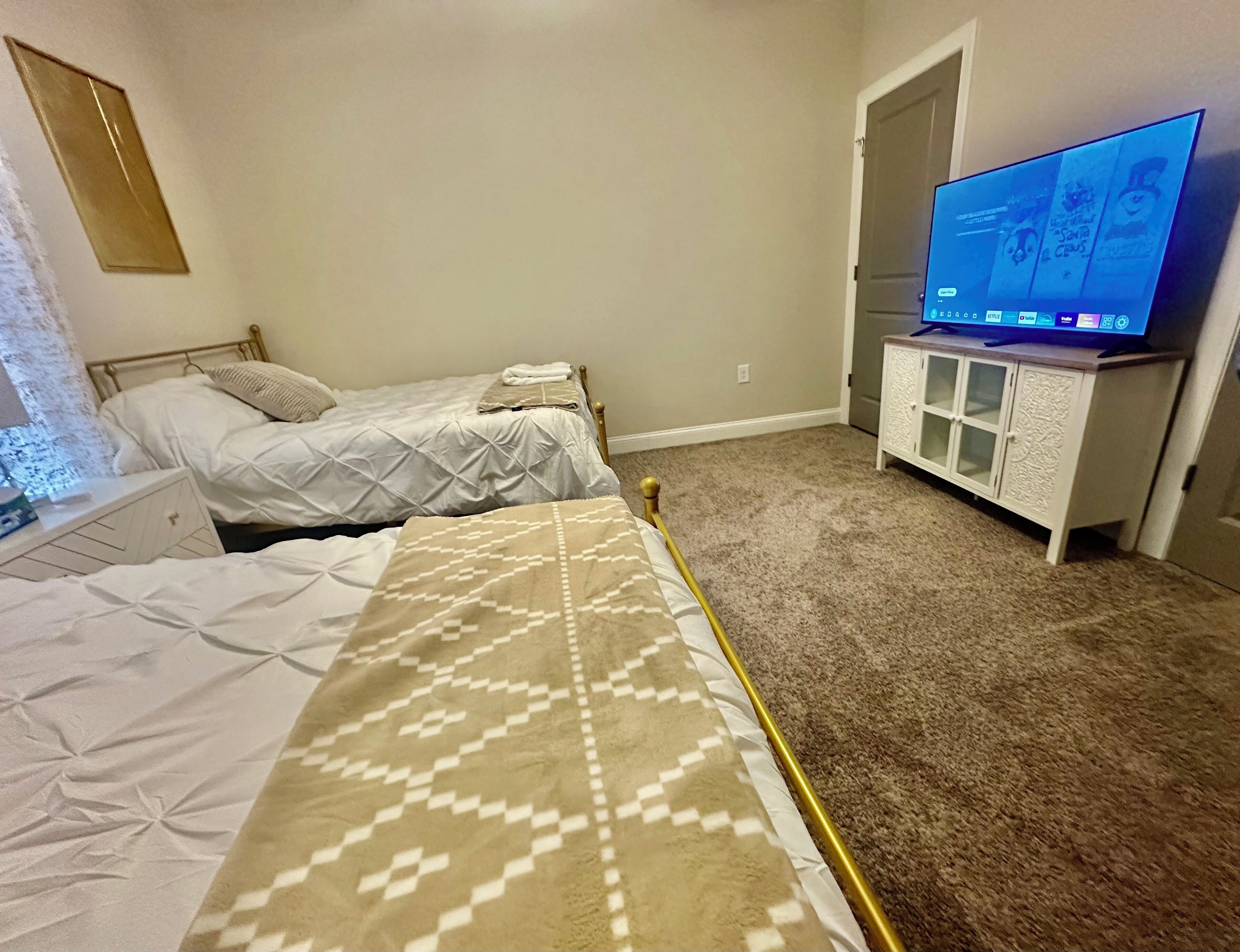 Ein Schlafzimmer mit zwei Betten, einem Fernseher auf einem Schrank und Teppichboden.