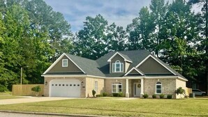 A two-story house with a garage, a front porch, and a landscaped lawn.