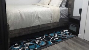 Ein Schlafzimmer mit einem Bett, einem Nachttisch, einem Teppich und drei gerahmten Bildern an der Wand.