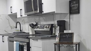 Eine moderne Küche mit Edelstahlgeräten, einer eingebauten Mikrowelle und einer Kaffeemaschine. Ein Schild an der Wand trägt die Aufschrift 'BE Amazing Today'.