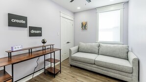 Ein modernes Wohnzimmer mit grauem Sofa, einem Holztisch und Bildern an den Wänden.