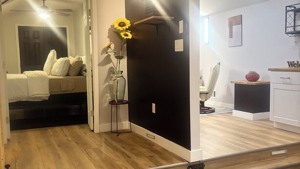 Ein modernes Hotelzimmer mit Holzboden, einem Bett mit weißer Bettwäsche, einer Vase mit Sonnenblumen und einer Wand in Schwarz.