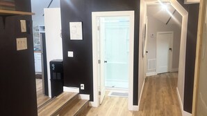 Ein moderner Flur mit Deckenventilator, einer Treppe und einer Tür zu einem Balkon.