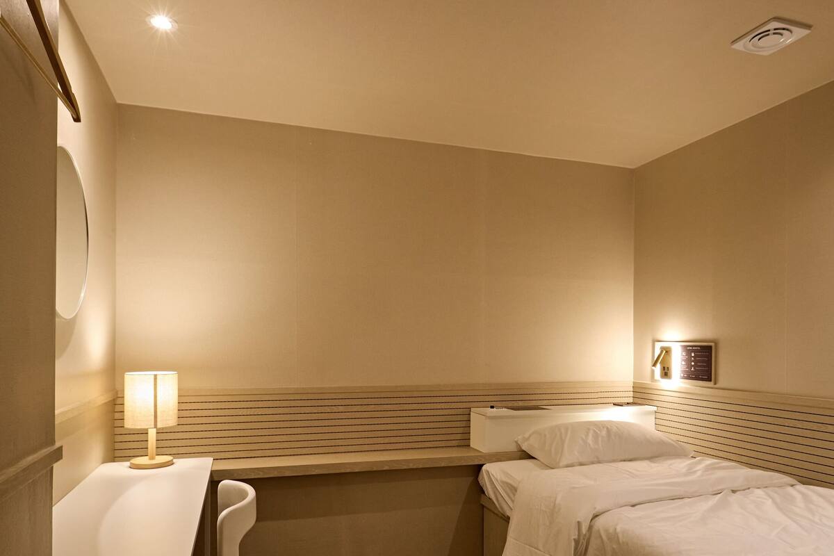 A hotel room with a bed, a desk, and a chair.