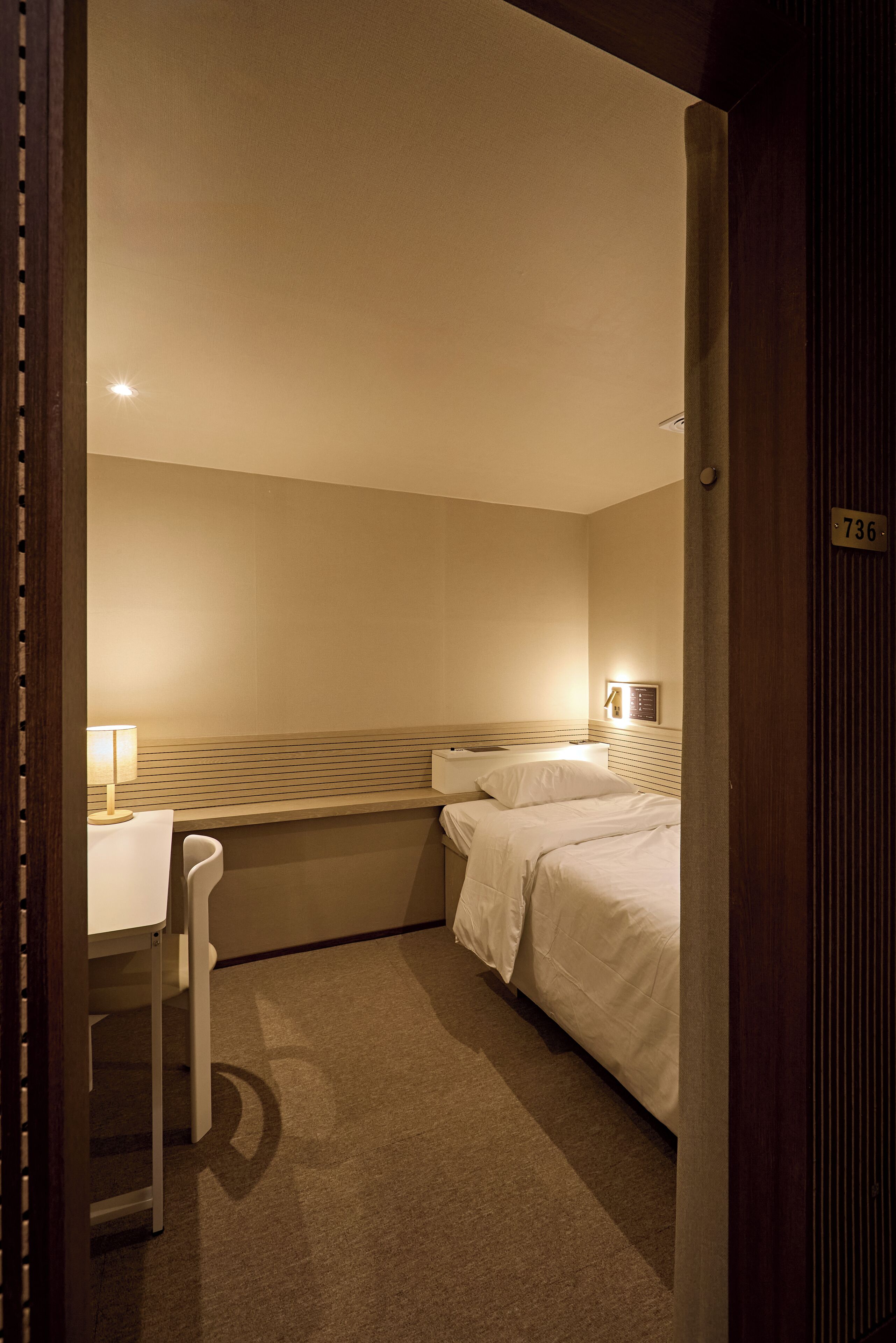 A hotel room with a bed, a desk, and a chair.