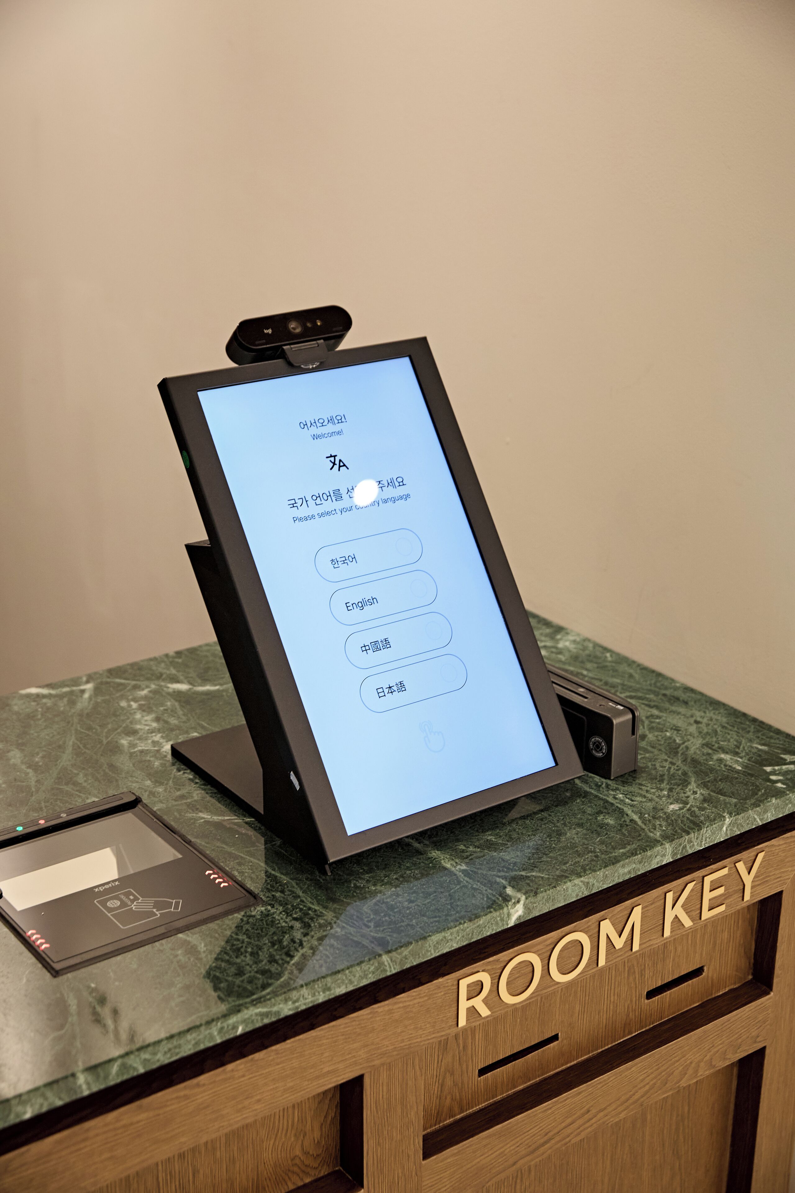 A digital room key station with a screen displaying a language selection menu.