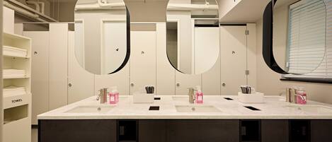 A modern bathroom with two sinks, large mirrors, and towel storage.