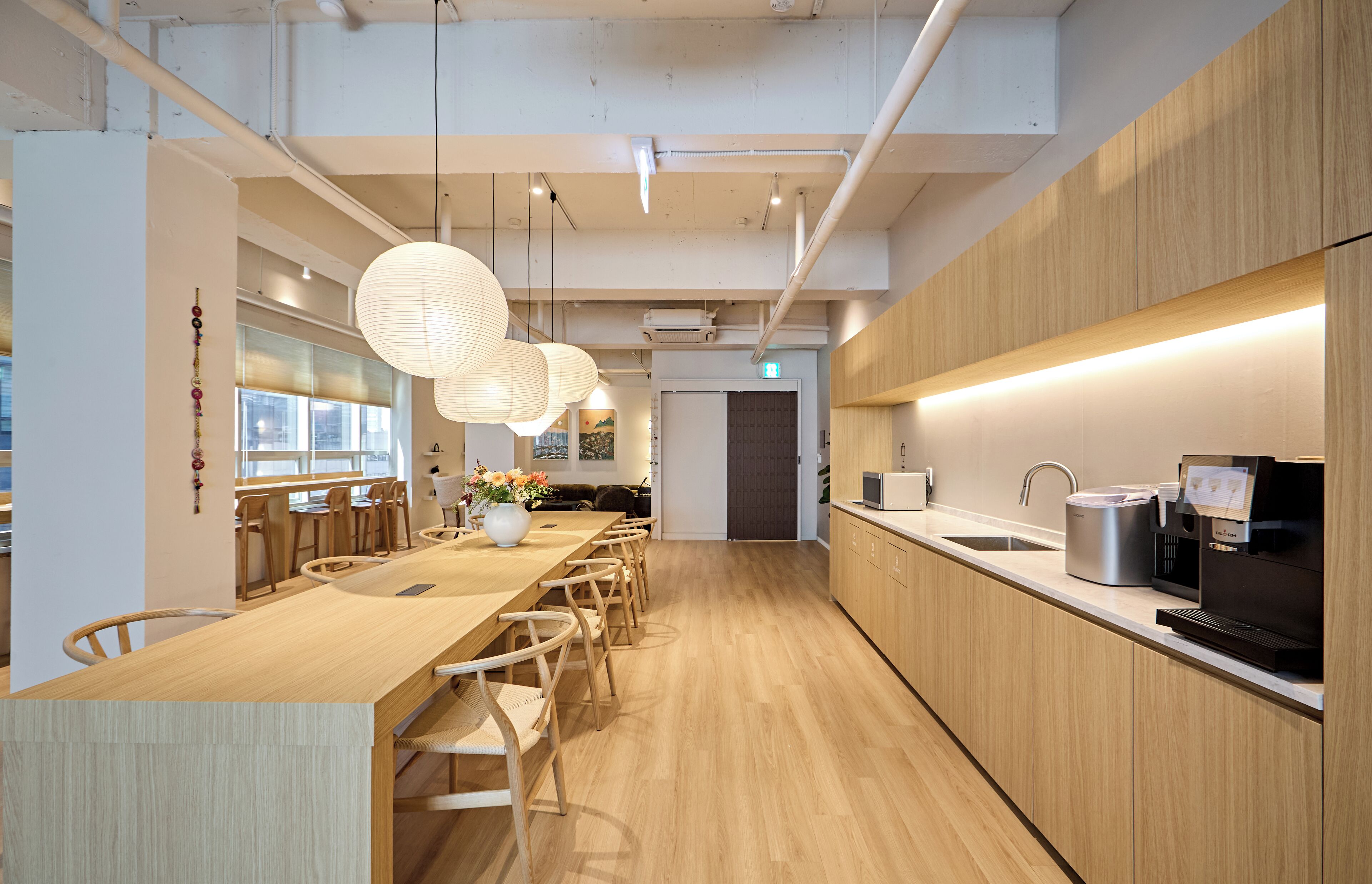 A modern kitchen with a wooden countertop, stainless steel appliances, and hanging paper lanterns.