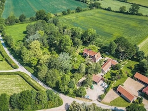 Vista aerea di una proprietà rurale con diversi edifici, una strada e campi circostanti.