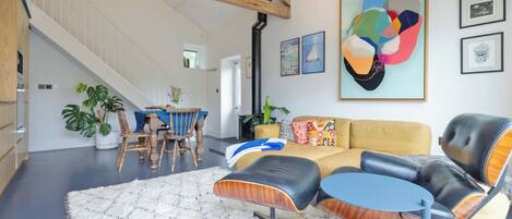 Un vaste espace de vie doté d’un haut plafond, d’un escalier et d’un coin repas avec une table et des chaises.
