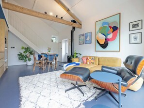 Ein geräumiger Wohnbereich mit hoher Decke, einer Treppe und einem Essbereich mit Tisch und Stühlen.