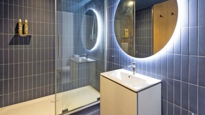 A modern bathroom with a glass-enclosed shower, a round mirror, and a white sink. - Sparrows Nest - UK50109 (Sparrow Green, near Dereham)