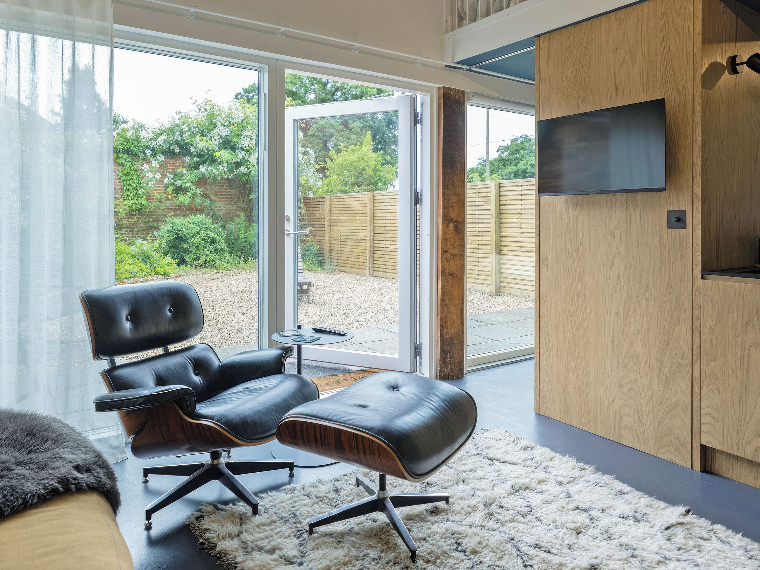 A modern room with a leather chair, a small table, and a television on a wooden cabinet.