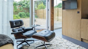 A modern room with a leather chair, a small table, and a television on a wooden cabinet. - Sparrows Nest - UK50109 (Sparrow Green, near Dereham)