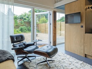 Ein modernes Zimmer mit einem Ledersessel, einem kleinen Tisch und einem Fernseher auf einer Holzkommode.