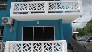 Un immeuble de deux étages doté de balcons, d’une grande fenêtre et d’un appareil de climatisation.