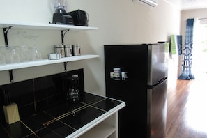 A kitchen with a black refrigerator, a coffee maker, and wine glasses on the counter.