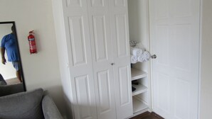 Une pièce avec une armoire blanche, un extincteur et une étagère où sont pliés des serviettes.