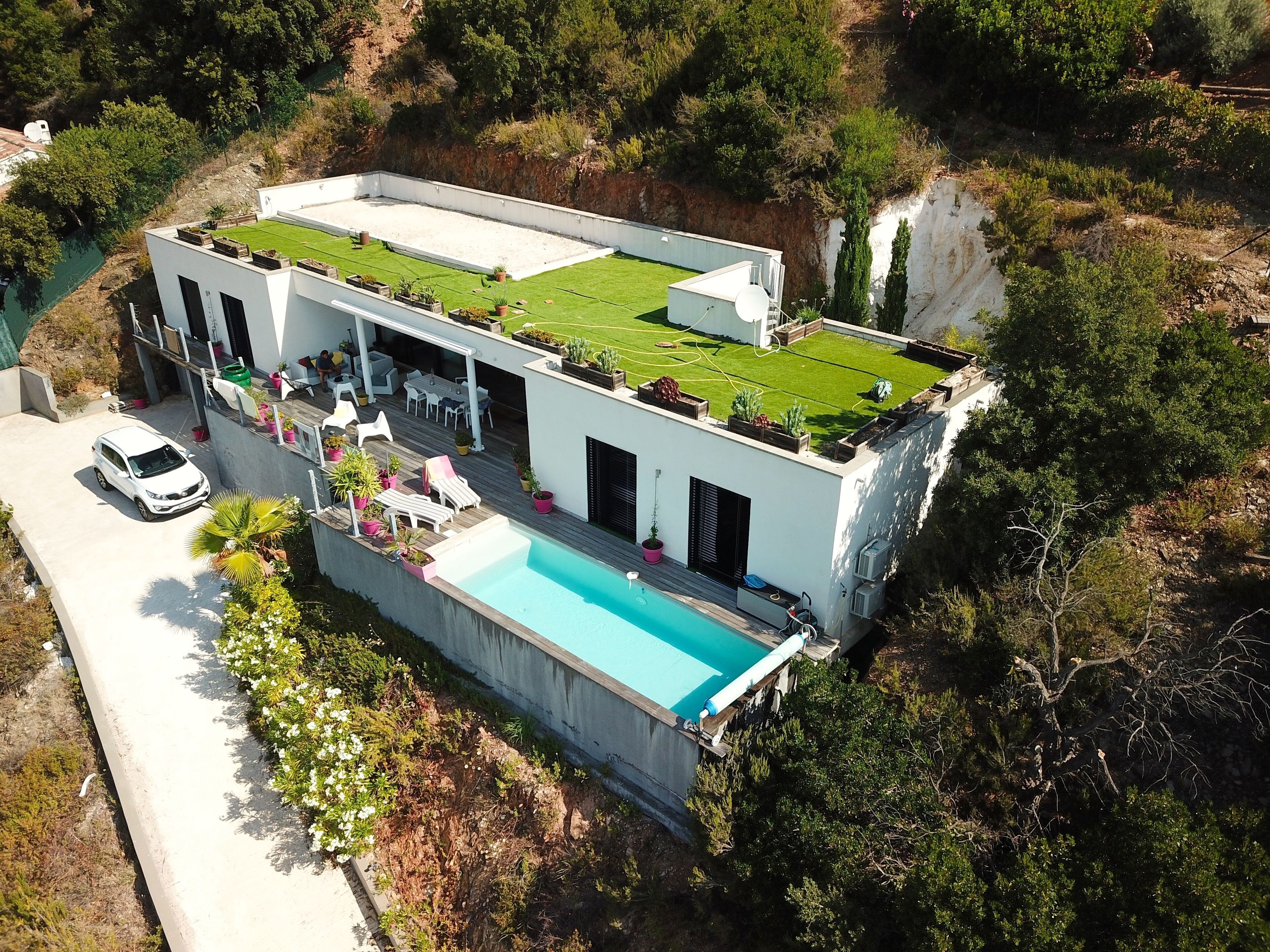 Une maison moderne dotée d’un jardin sur le toit, d’une piscine et d’un espace patio.