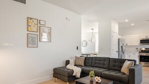 A modern living room with a sectional sofa, a coffee table, and artwork on the wall. - Modern, Spacious & Peaceful 4B/3B House (Chandler)