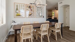 A dining area with a long table, six wicker chairs, and three framed artworks on the wall. - Modern, Spacious & Peaceful 4B/3B House (Chandler)