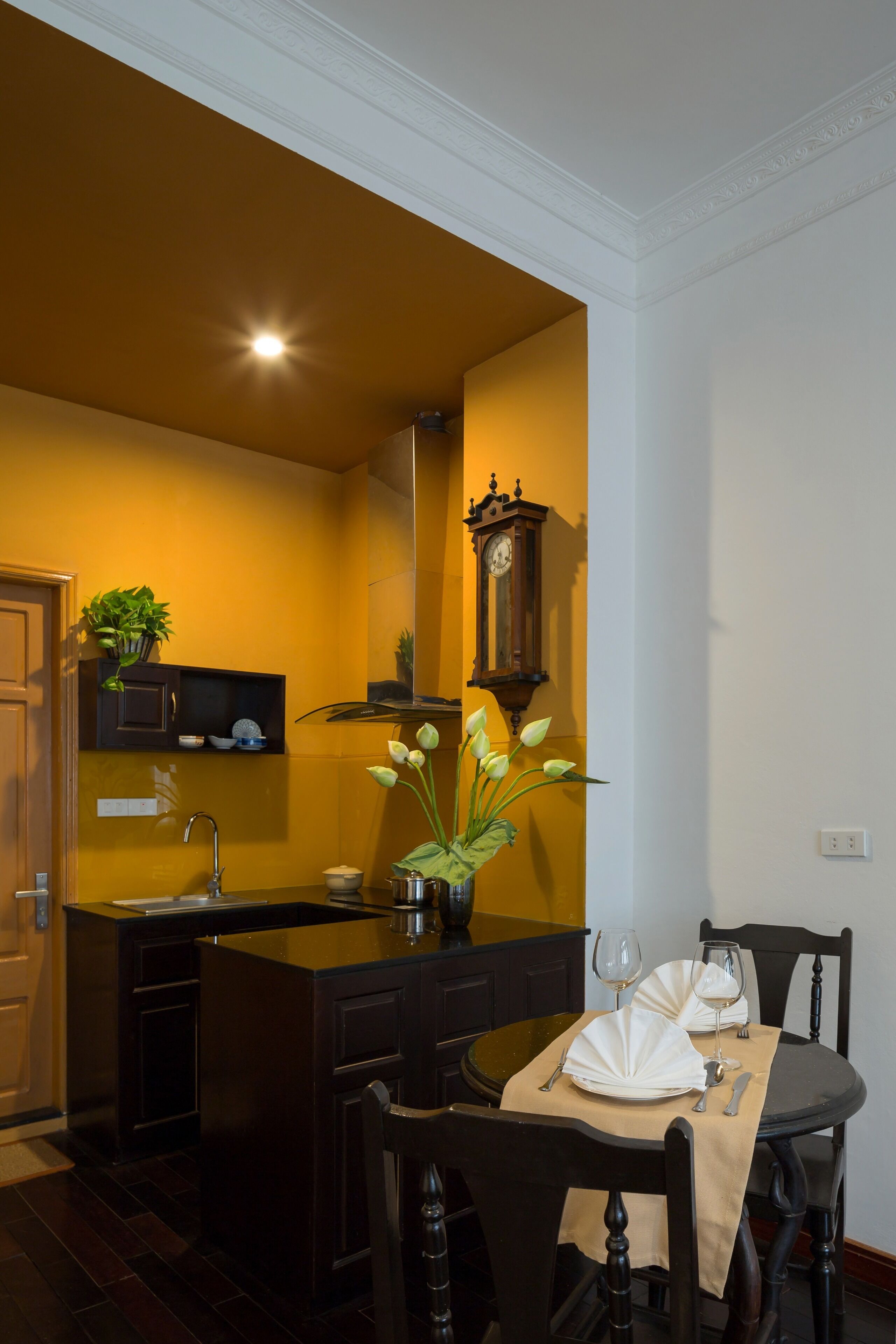 Cocina compacta con comedor, que incluye un fregadero, un reloj y una planta.
