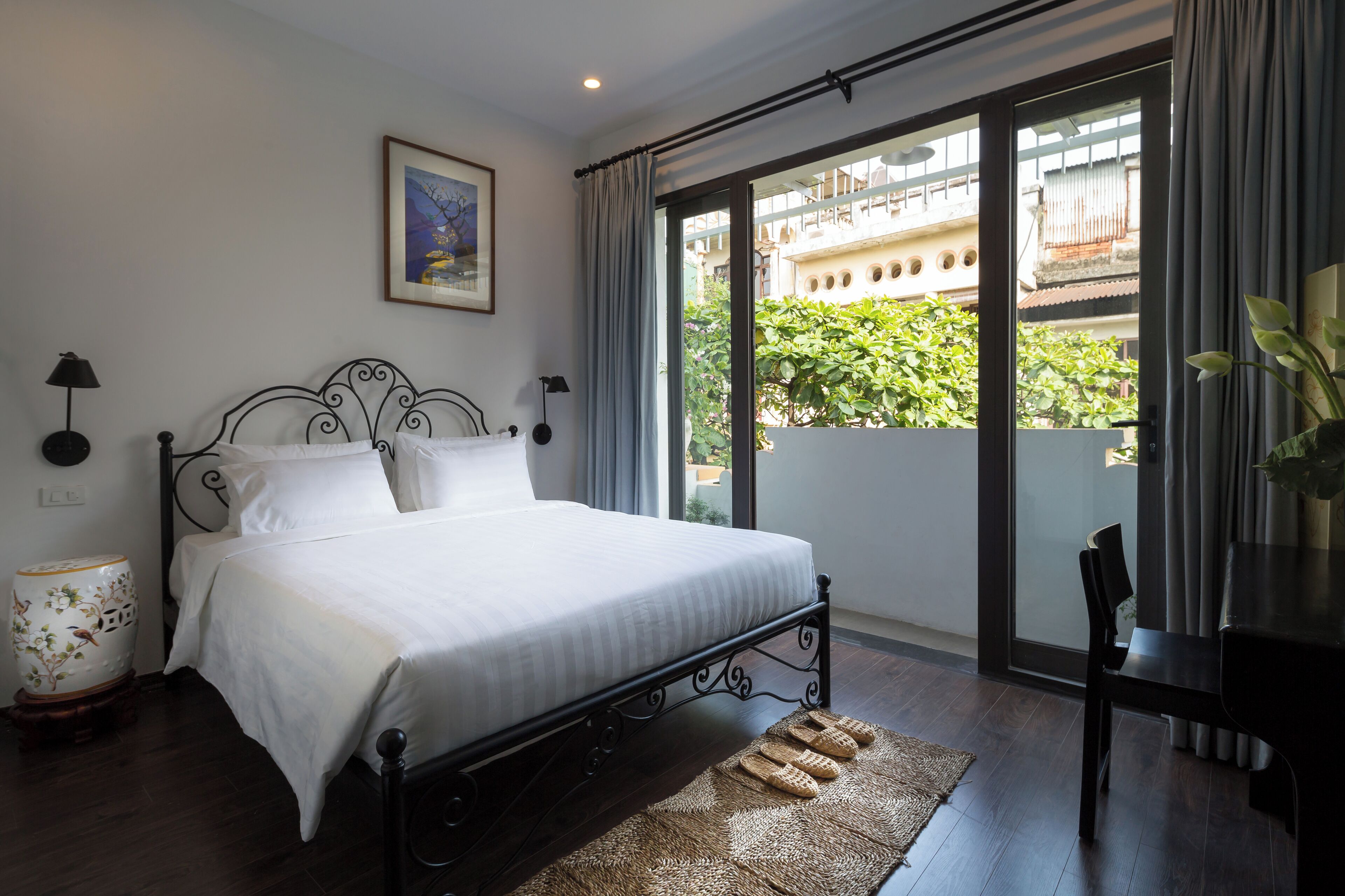 A bedroom with a bed, a nightstand, a lamp, a chair, and a view of the outside balcony.