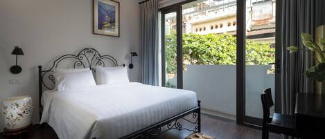 A bedroom with a bed, a nightstand, a lamp, a chair, and a view of the outside balcony.