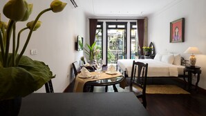 A hotel room with a dining area, a bed, and a view of the outside. - Centraltique Downtown Living (Hanoi)
